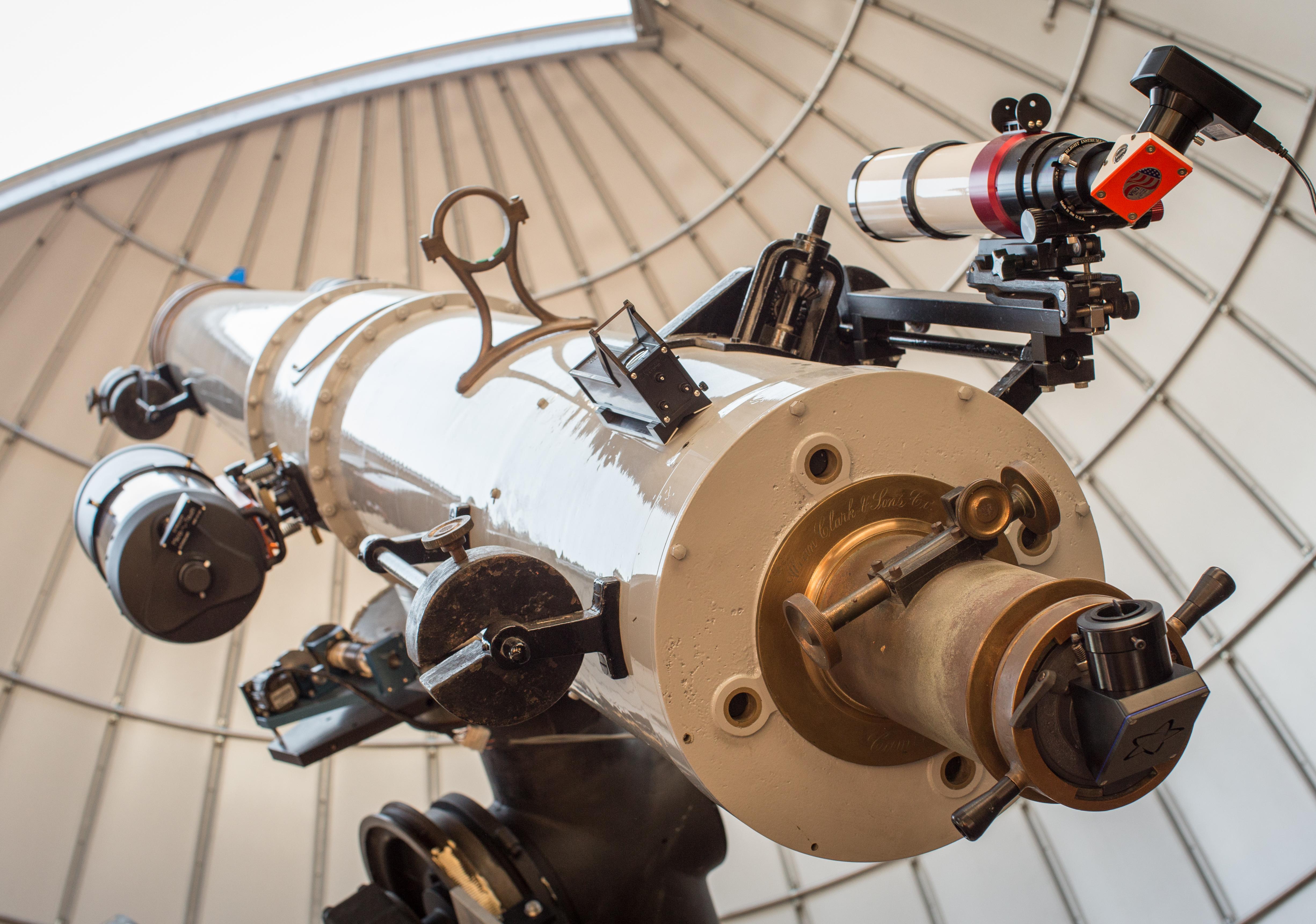 Large white telescope points towards the afternoon sky through an open observatory dome