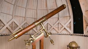 Brass and wood telescope stands on base under a fake observatory dome 