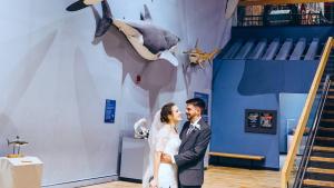 Bride and groom pose under Finn the Megalodon at the South Carolina State Museum