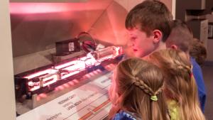 Two boys and two girls observing a maser and laser demonstration display