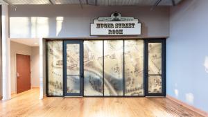 Exterior glass wall of meeting room shows sepia toned illustrated map of Columbia with sign above that reads Huger Street Room