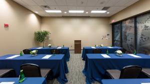 Medium sized room with tables with blue tablecloths set up facing a wooden podium