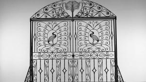Large black iron gate on display featuring scrollwork and representations of egrets on each side