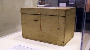 Rectangular, grayish colored box c. 1876 with hinged lid on exhibition