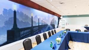 Mural of bridge on left side wall of room with table set up in front with blue table cloth