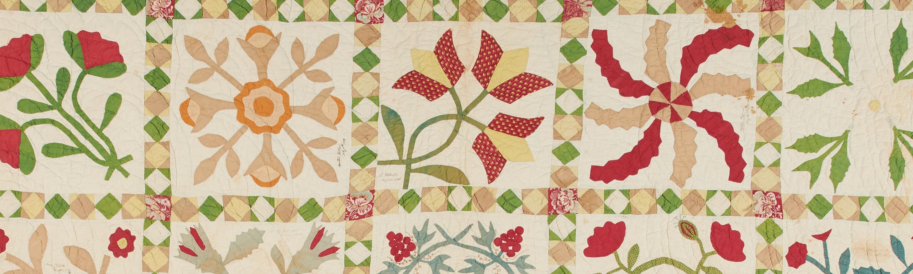 a quilt with green, red and yellow flowers on a cream colored background