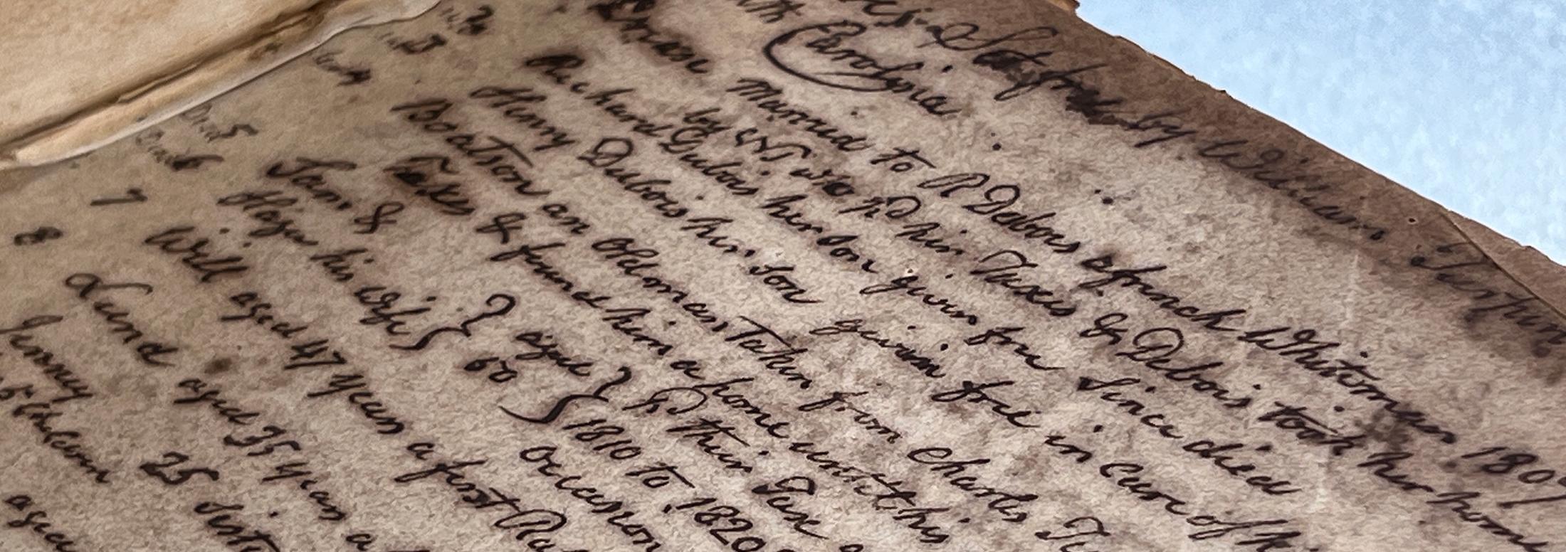 Close up image of an aged, sepia colored page in a book with lines of black handwritten text in cursive script