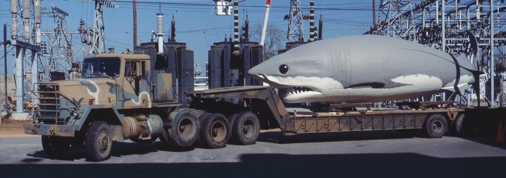 Giant Megalodon replica sits on the back on a National Guard flatbed truck in a parking area