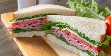 White bread sandwich cut into triangles with ham, tomato, cheese lettuce