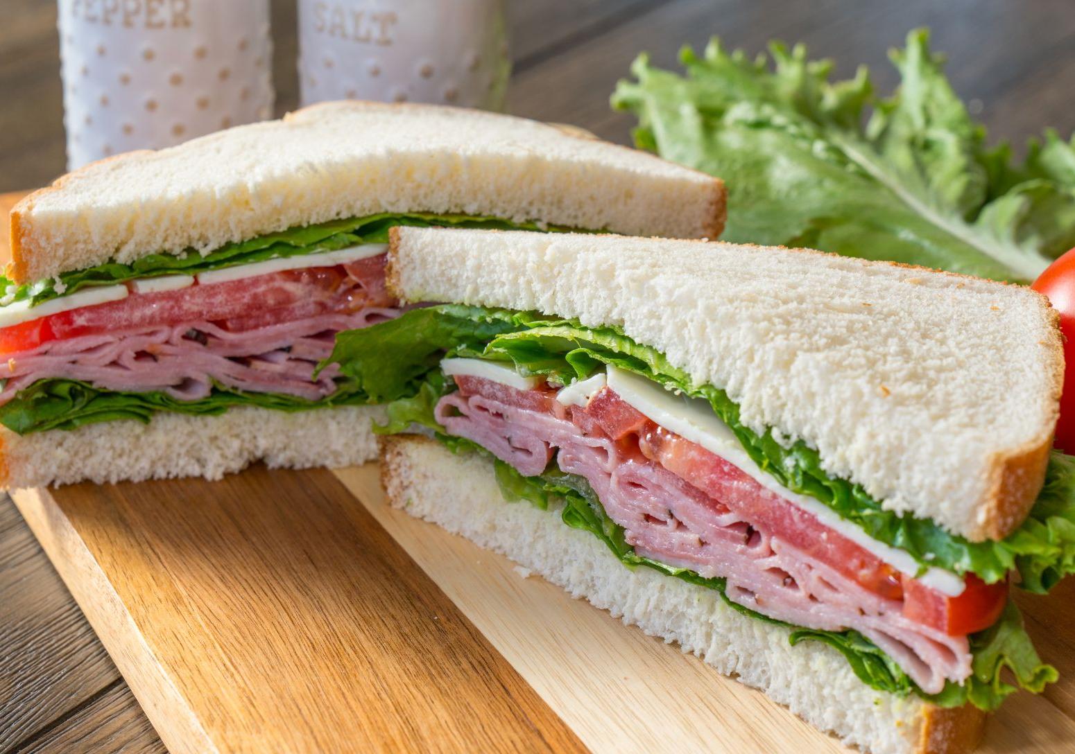 White bread sandwich cut into triangles with ham, tomato, cheese lettuce