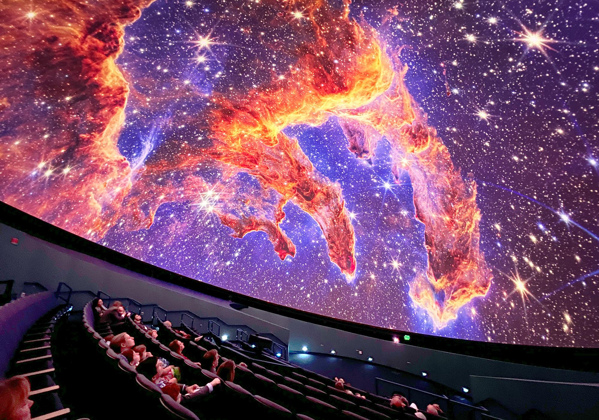 Guests in the planetarium dome look up at projection of the Pillars of Earth on the planetarium dome