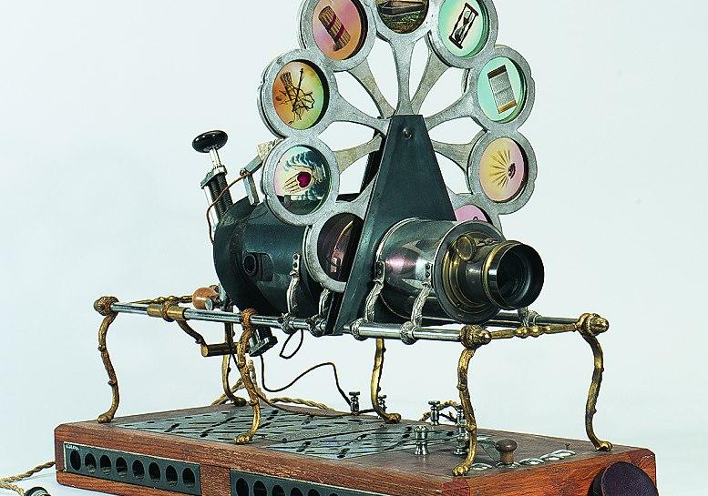 Antique projector with round slide feeder with spokes radiating from the center that holds one glass slide per spoke 