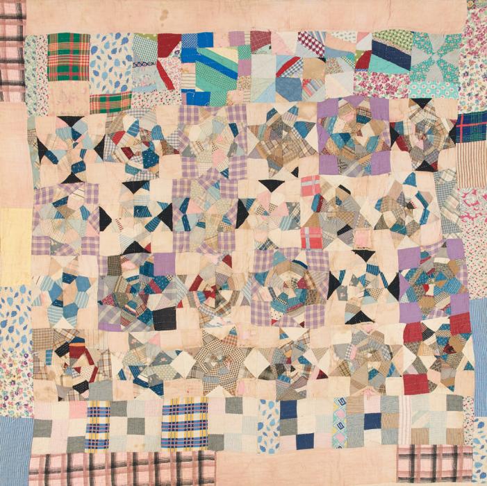 Crazy style quilt in scraps of light blue gingham, a variety of plaids, dark blues and reds. Overall the quilt has a lighter color theme.
