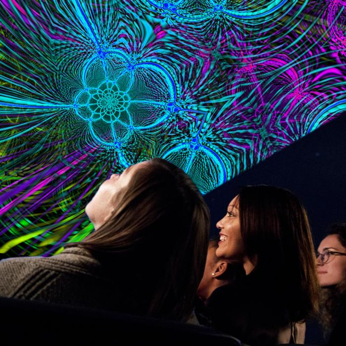 Individuals seated in the Planetarium looking up at the Friday Night Laser Lights